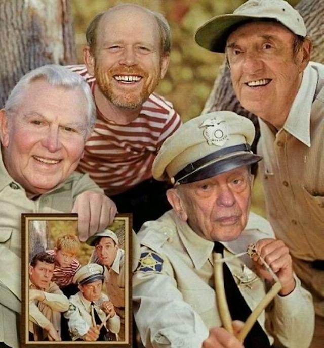 A heartwarming reunion photo of the iconic cast members from The Andy Griffith Show, featuring Ron Howard, Andy Griffith, Don Knotts, and Jim Nabors holding a picture of their younger selves during the show's original run.