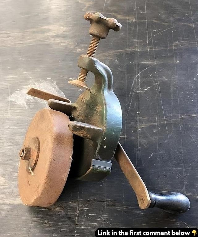 This image showcases a classic hand crank grinder, a versatile tool used for sharpening knives, axes, and tools by rotating the handle manually to grind metal against the stone